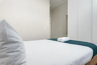 a white bed with a rolled up towel on it at The Axis Luxury Apartments in Cape Town