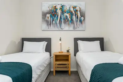 a bedroom with two beds and a table with a painting at The Axis Luxury Apartments in Cape Town
