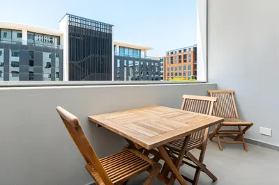 a wooden table and chairs on a balcony with a window at The Axis Luxury Apartments in Cape Town