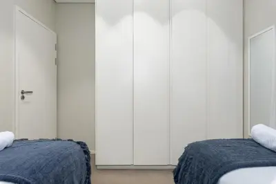 two beds in a bedroom with white cabinets at The Axis Luxury Apartments in Cape Town