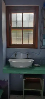 a bathroom with a white sink under a window at Gecko Cottage at Artemis in Franschhoek