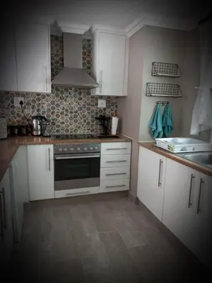 a kitchen with white cabinets and a stove at Bay-Side Apartment, Gordon's Bay in Gordonʼs Bay