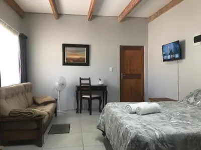 a bedroom with a bed and a chair and a table at Kunsvilla in Durbanville