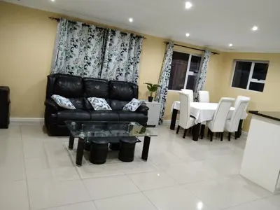 a living room with a black leather couch and a table at 24 Wrench Glenlilly Parow in Cape Town