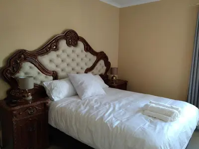 a bedroom with a white bed with a large headboard at 24 Wrench Glenlilly Parow in Cape Town