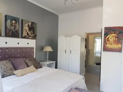 a bedroom with a bed and paintings on the wall at Somerset West All Stay 1 in Somerset West