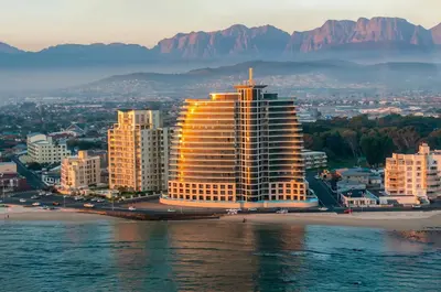 a large building on the beach with mountains in the background at Luxury Ocean View 1203 in Cape Town