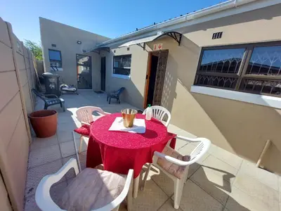 a red table and chairs on a patio at Finca Guest House in Cape Town