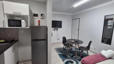 a kitchen with a refrigerator and a table and chairs at Finca Guest House in Cape Town