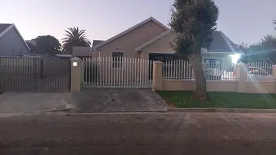 a house with a white fence and a tree at Finca Guest House in Cape Town
