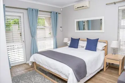 a bedroom with a large white bed with blue pillows at A Touch of Country in Stellenbosch