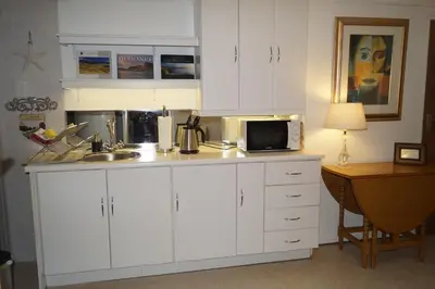 a kitchen with white cabinets and a sink and a microwave at Valentines Hermanus in Hermanus
