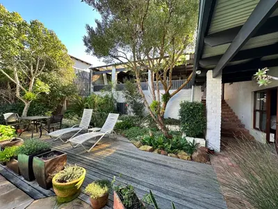 a backyard with two chairs and a wooden deck at Hidden Gem on Onrus River in Hermanus