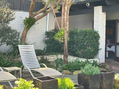 two white chairs and plants in a garden at Hidden Gem on Onrus River in Hermanus