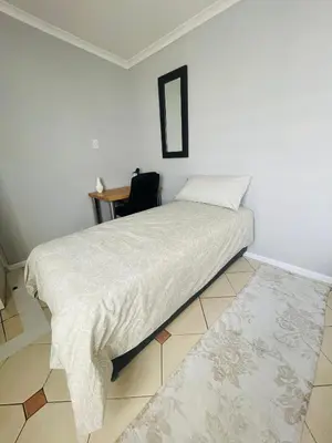 a bedroom with a bed and a desk and a chair at Sixth Avenue Residence Halaal Accommodation Cape Town in Cape Town