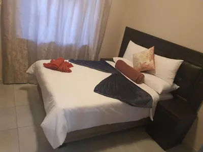 a bed with two blankets and pillows on it at Mabel Guesthouse in Cape Town