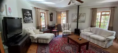 a living room with white furniture and a flat screen tv at Wine Route 44 Guesthouse in Somerset West