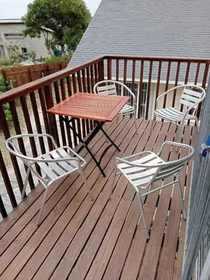 a wooden deck with a table and chairs on it at Aloe Ocean Flatlet in Bettyʼs Bay