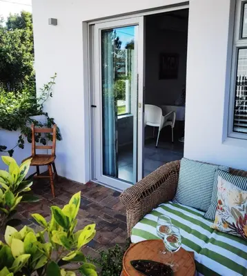 a patio with a couch and a table with wine glasses at Oak Village in Stellenbosch