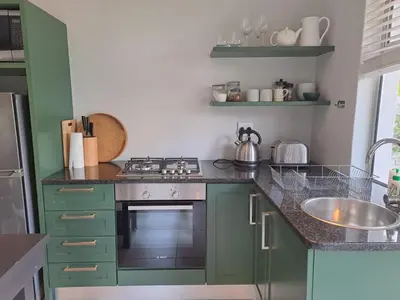 a kitchen with green cabinets and a stove and a sink at Oak Village in Stellenbosch