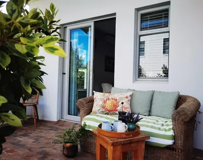a wicker couch on a patio with a table at Oak Village in Stellenbosch
