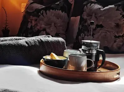 a tray with a tea set on a bed at Oak Village in Stellenbosch