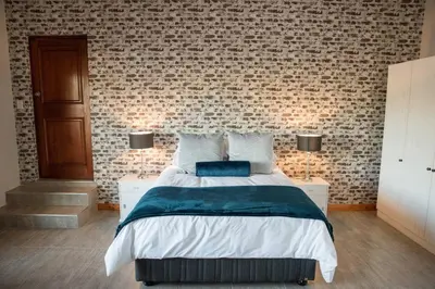 a bedroom with a bed and a brick wall at Sol Montis Guest Cottage in Paarl