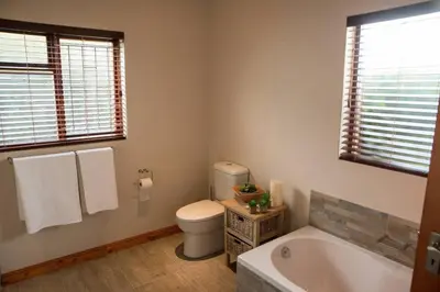 a bathroom with a tub and a toilet and a window at Sol Montis Guest Cottage in Paarl