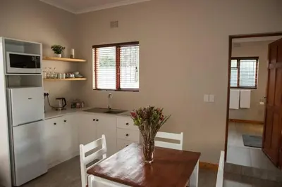 a kitchen with a table with a vase of flowers on it at Sol Montis Guest Cottage in Paarl