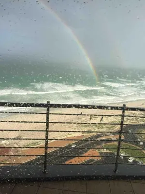 a rainbow over a beach with a fence and the ocean at Horizon Bay 1502 in Cape Town