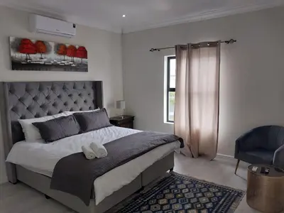 a bedroom with a large bed and a window at LND GUEST HOUSE in Bloubergstrand