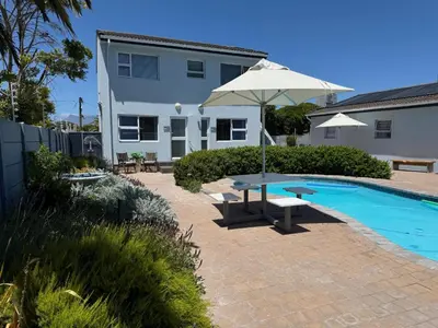 a patio with a table and an umbrella next to a pool at Southeaster in Bloubergstrand