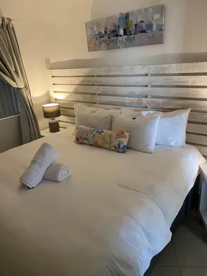 a large white bed with two pillows on it at Seaview Sunset Boutique Apartments Gordonsbay Solar powered in Cape Town