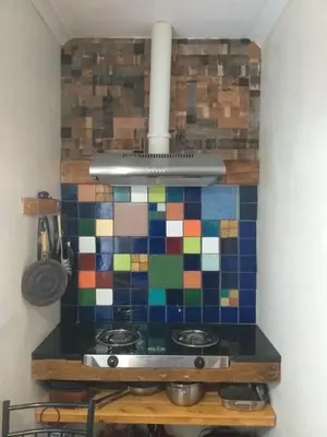 a kitchen with a stove with a colorful tiled wall at Sol Y Sombra in Bettyʼs Bay