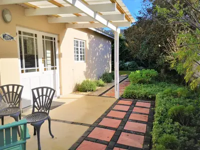 a patio with chairs and a white pergola at Seashell Cottage in Hermanus