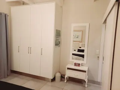 a white bedroom with a large white cabinet at Seashell Cottage in Hermanus