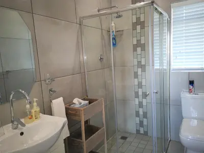 a bathroom with a shower and a sink and a toilet at Seashell Cottage in Hermanus