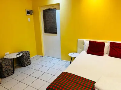 a bedroom with a bed and a yellow wall at Mowetu Guest House in Cape Town