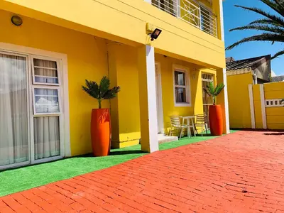 a yellow house with orange vases on the side of it at Mowetu Guest House in Cape Town
