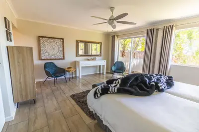 a bedroom with a bed and a desk and chairs at Val de Vine in Stellenbosch