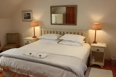 a bedroom with a large white bed with a mirror at 3 on Roux in Franschhoek