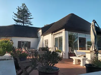 a house with a patio with a table and chairs at The Sanctuary Guest House Estate in Cape Town