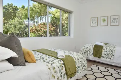 a bedroom with two beds and a large window at Fernkloof Cottage in Hermanus