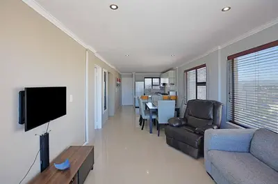 a living room with a couch and a flat screen tv at Nautica 2 Bedroom Beachfront Apartment with Sea Views in Bloubergstrand