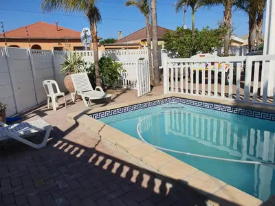 a swimming pool in a backyard with a white fence at The White House Lodge in Cape Town