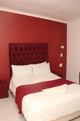 a bedroom with a large bed with a red wall at The White House Lodge in Cape Town