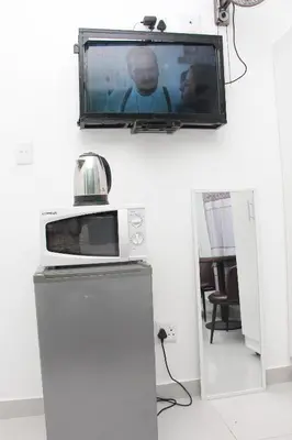 a television on a wall with a microwave and a refrigerator at The White House Lodge in Cape Town