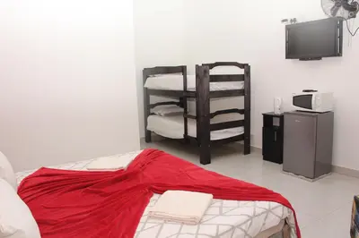 a living room with a bed and a tv and a room at The White House Lodge in Cape Town