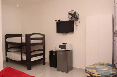 a room with a tv and a chair and a microwave at The White House Lodge in Cape Town