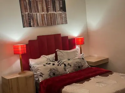 a bedroom with a bed with a red headboard and two lamps at Peaceful getaway in Cape Town